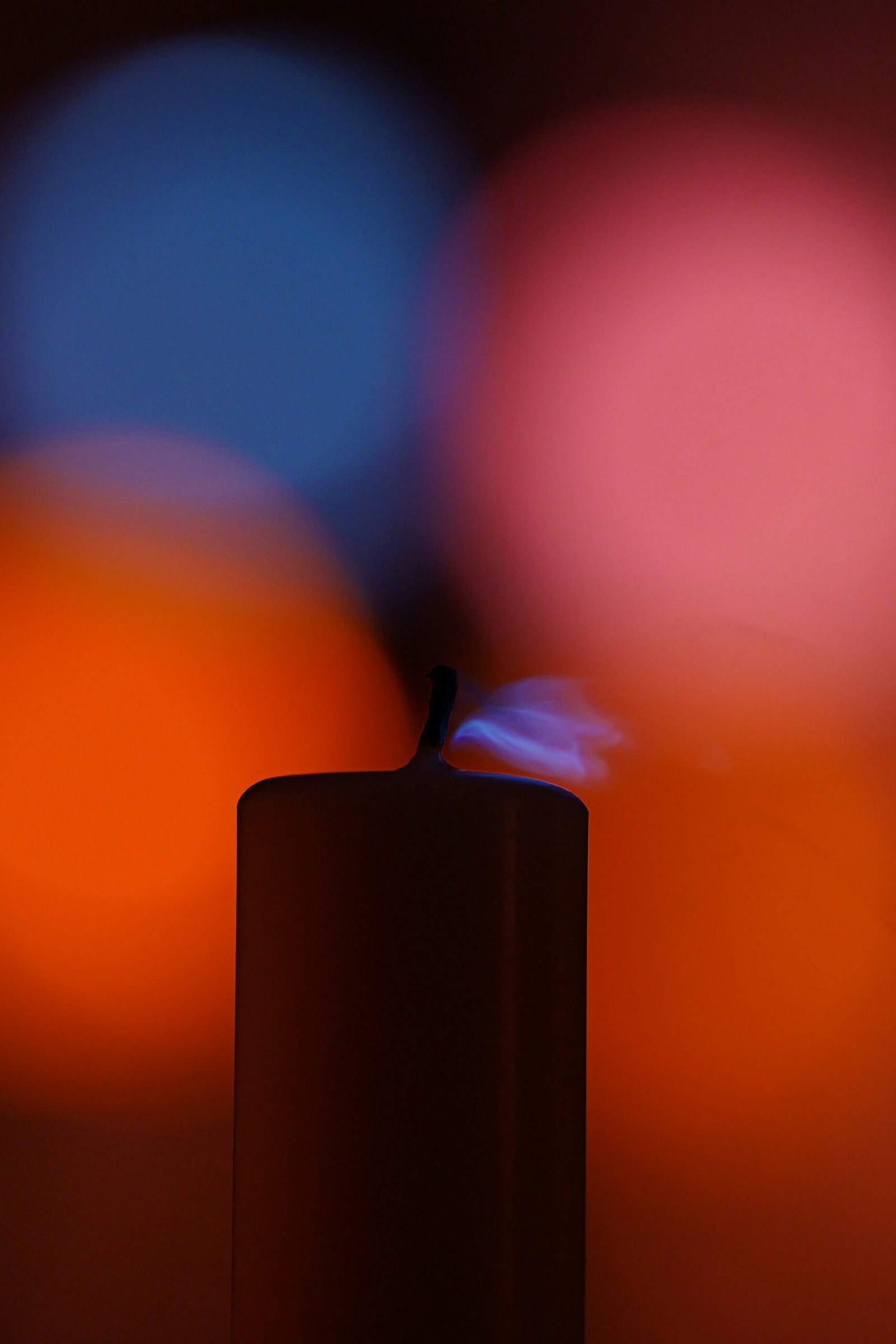 Bougie allumée avec flamme sur fond coloré orange et bleu pour illustrer les jeux de cire BDSM